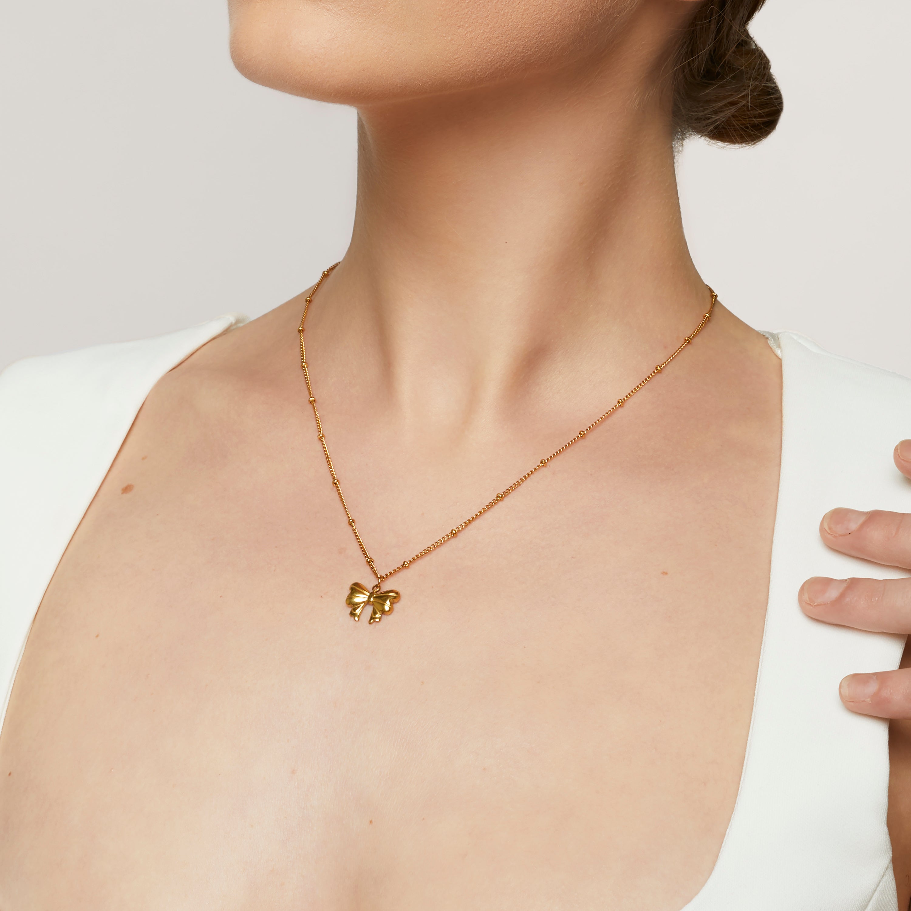 A model wearing the Wendy Necklace - the perfect combination of style and durability. This versatile accessory, made from non-tarnish 18K gold-plated stainless steel, is water-resistant and suitable for any occasion. With its adjustable design, it's the only necklace you'll ever need.