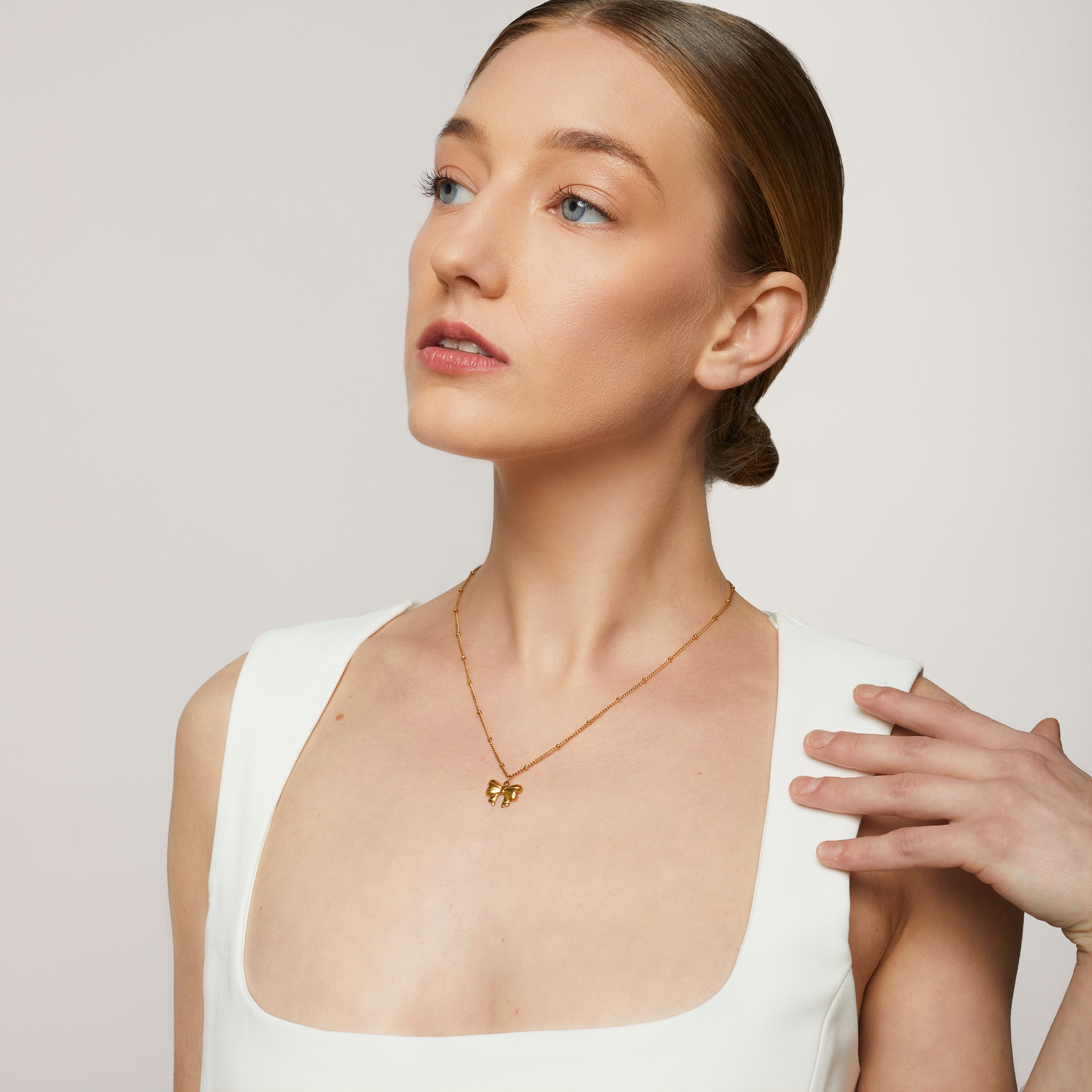 A model wearing the Wendy Necklace - the perfect combination of style and durability. This versatile accessory, made from non-tarnish 18K gold-plated stainless steel, is water-resistant and suitable for any occasion. With its adjustable design, it's the only necklace you'll ever need.