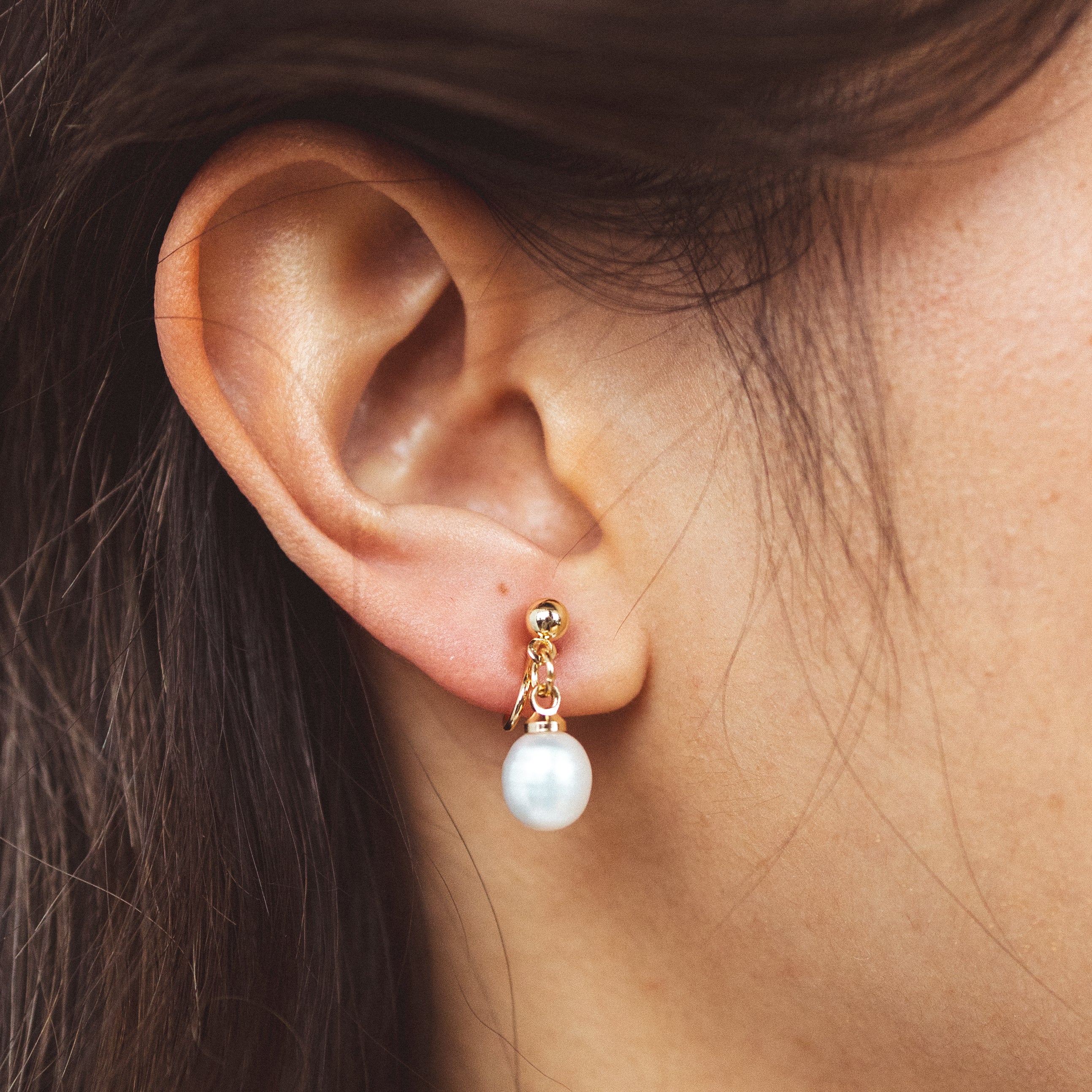 A model wearing the Elio Clip On Earrings. Designed for all ear types, these elegant earrings provide a secure hold for up to 24 hours. Enjoy unparalleled comfort and style, perfect for those with sensitive or stretched ears. Upgrade your style effortlessly with Elio.