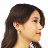 A model wearing the Elio Clip On Earrings. Designed for all ear types, these elegant earrings provide a secure hold for up to 24 hours. Enjoy unparalleled comfort and style, perfect for those with sensitive or stretched ears. Upgrade your style effortlessly with Elio.