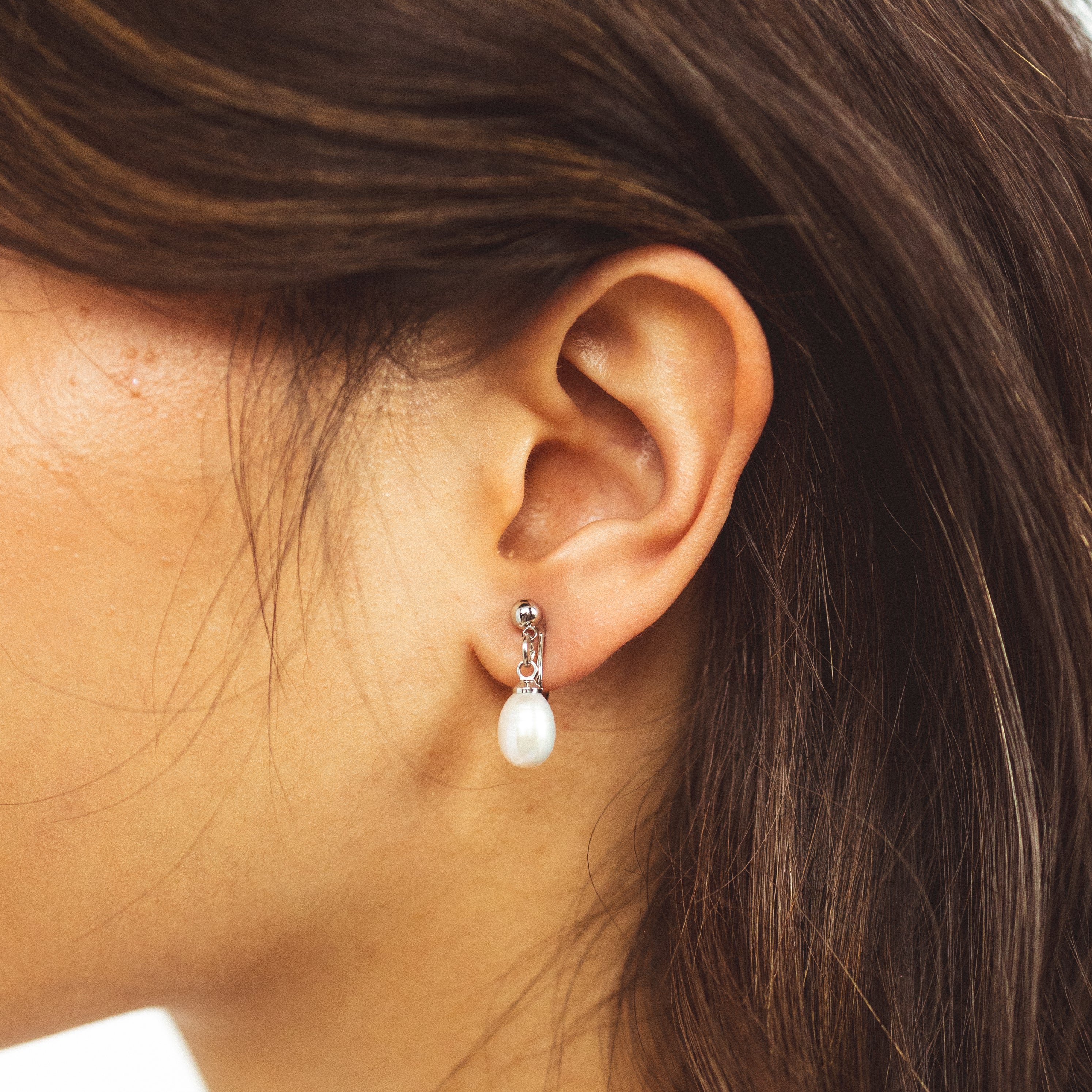 A model wearing the Elio Clip On Earrings. Designed for all ear types, these elegant earrings provide a secure hold for up to 24 hours. Enjoy unparalleled comfort and style, perfect for those with sensitive or stretched ears. Upgrade your style effortlessly with Elio.