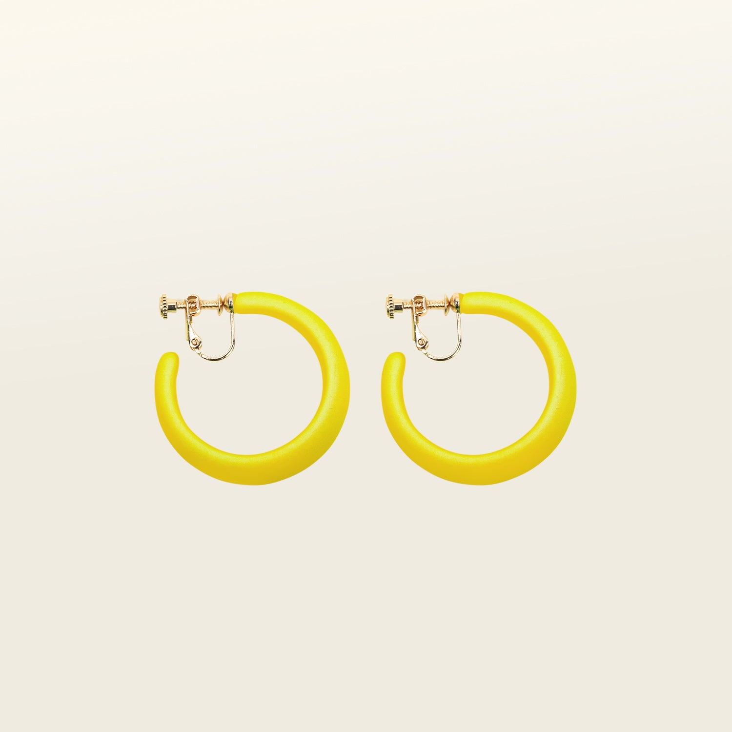 Model adorning stylish yellow clip-on hoop earrings with manual adjustability. These earrings are perfect for all ear types, ensuring a secure and comfortable hold. Crafted from gold tone copper metal alloy and acrylic. 