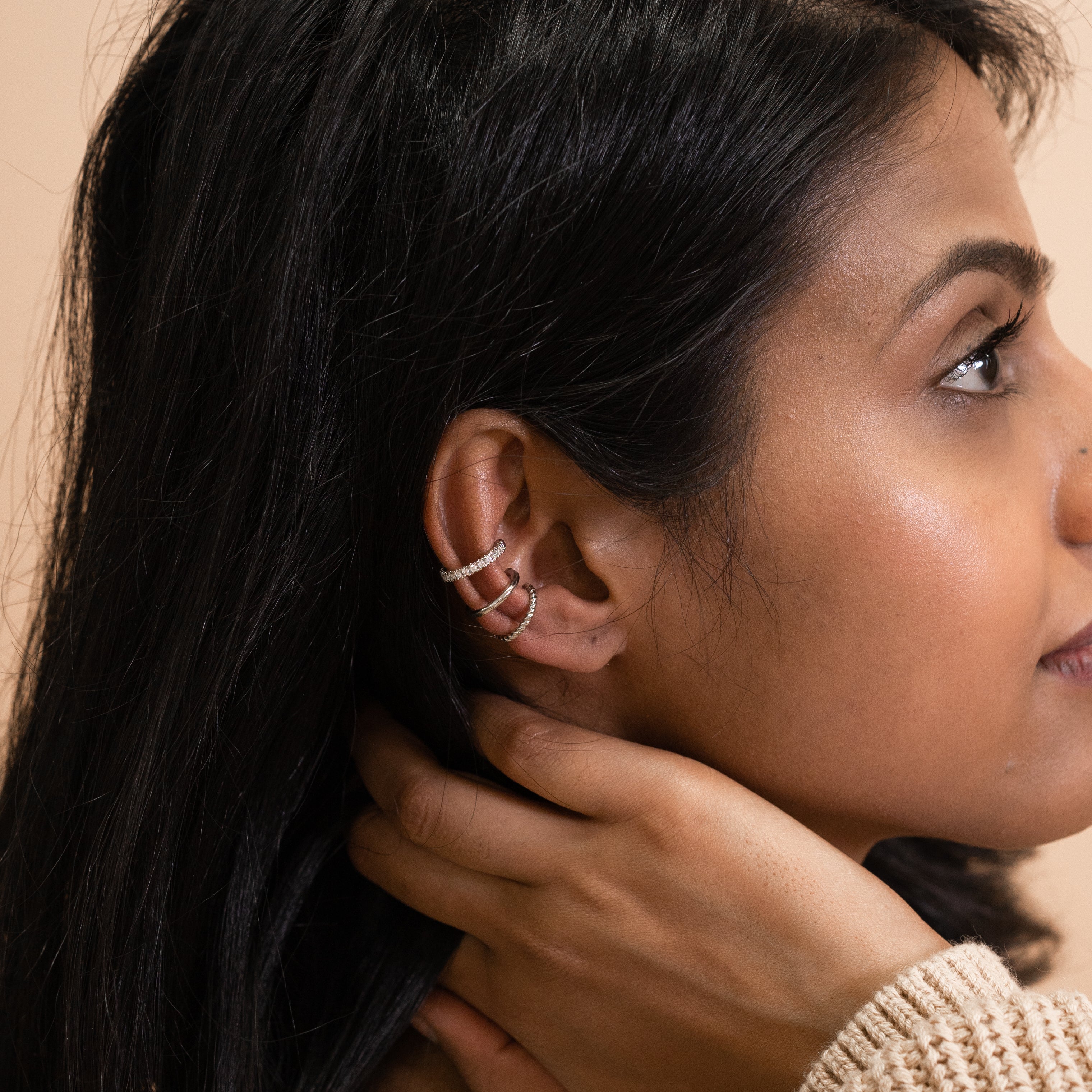A model wearing the Silver Trio Ear Cuffs Set is composed of silver tone plated alloy and Cubic Zirconia. It is supplied with three pieces, and a Gold version is available. Each ear cuff is secured with a closure so you can wear securely and comfortably.