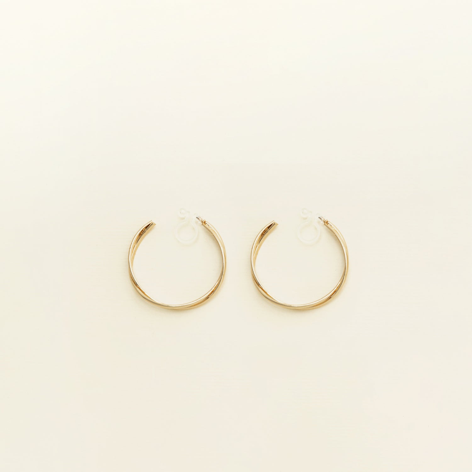 Image of the Gold Vienna Hoop Clip-On Earrings feature a resin clip-on closure with medium secure hold. The earrings are suitable for all types of ears, with an average comfortable wear time of 8-12 hours. No adjustments can be made. Constructed with gold tone metal alloy, these earrings are also available in silver.