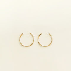 Image of the Gold Vienna Hoop Clip-On Earrings feature a resin clip-on closure with medium secure hold. The earrings are suitable for all types of ears, with an average comfortable wear time of 8-12 hours. No adjustments can be made. Constructed with gold tone metal alloy, these earrings are also available in silver.