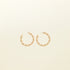Image of the Gold Wave Hoop Clip-On Earrings boast a closure type of resin clip-on, ideal for the vast majority of ear types. Average wear duration ranges from 8-12 hours, offering medium secure hold with no ability to adjust. Crafted from gold tone metal alloy, this item comes as one pair and is also available in silver.