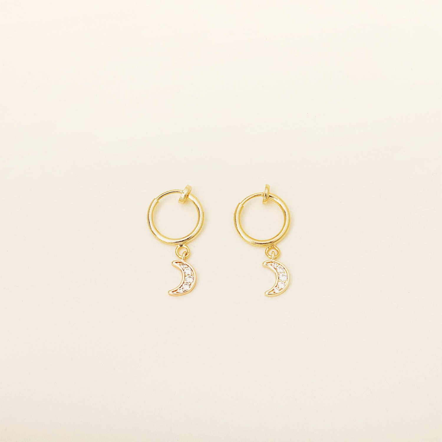 Image of the Moon Charm Clip on Earrings feature a sliding spring closure type, specifically designed for those with small or thinner ear lobes. This type of closure ensures a very secure hold and an adjustable fit to accommodate different ear thicknesses. Sold as a single pair, these earrings are crafted from brass and feature cubic zirconia details. Typically suitable for wear of 2-4 hours.