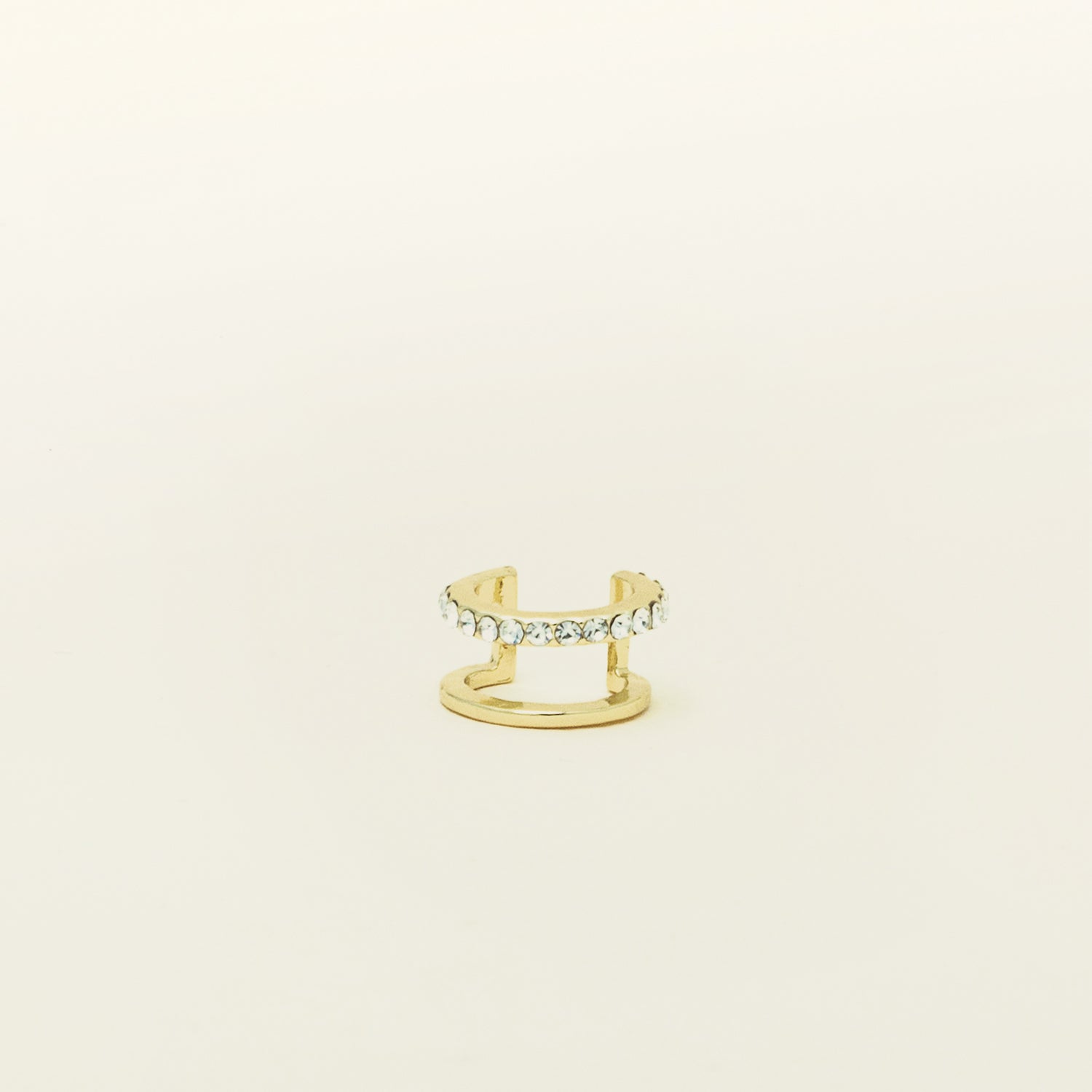 Image of a striking multi-band ear cuff, a contemporary fusion of gold-tone plated alloy and glistening strass. Expertly crafted to suit both men and women, this stylish accessory is intended to be worn along the conch of the ear, allowing you to make a bold fashion statement with this eye-catching piece