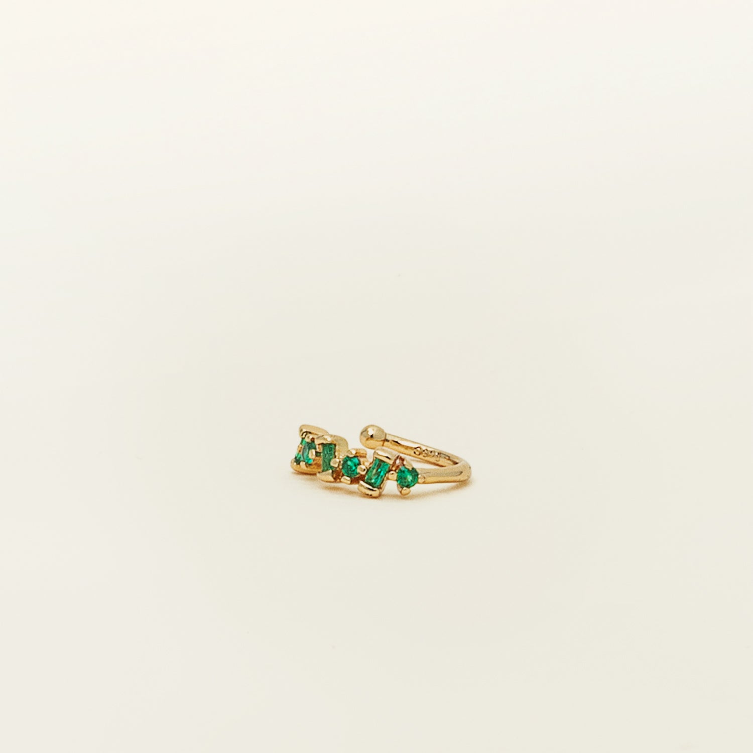 Catalogue image of the modern Emerald Green Pavé Cluster Ear Cuff. Featuring a 925 Sterling Silver gold toned finish and a variety of Cubic Zirconia gemstone colors, this unique ear cuff will add a touch of sophistication to any outfit.