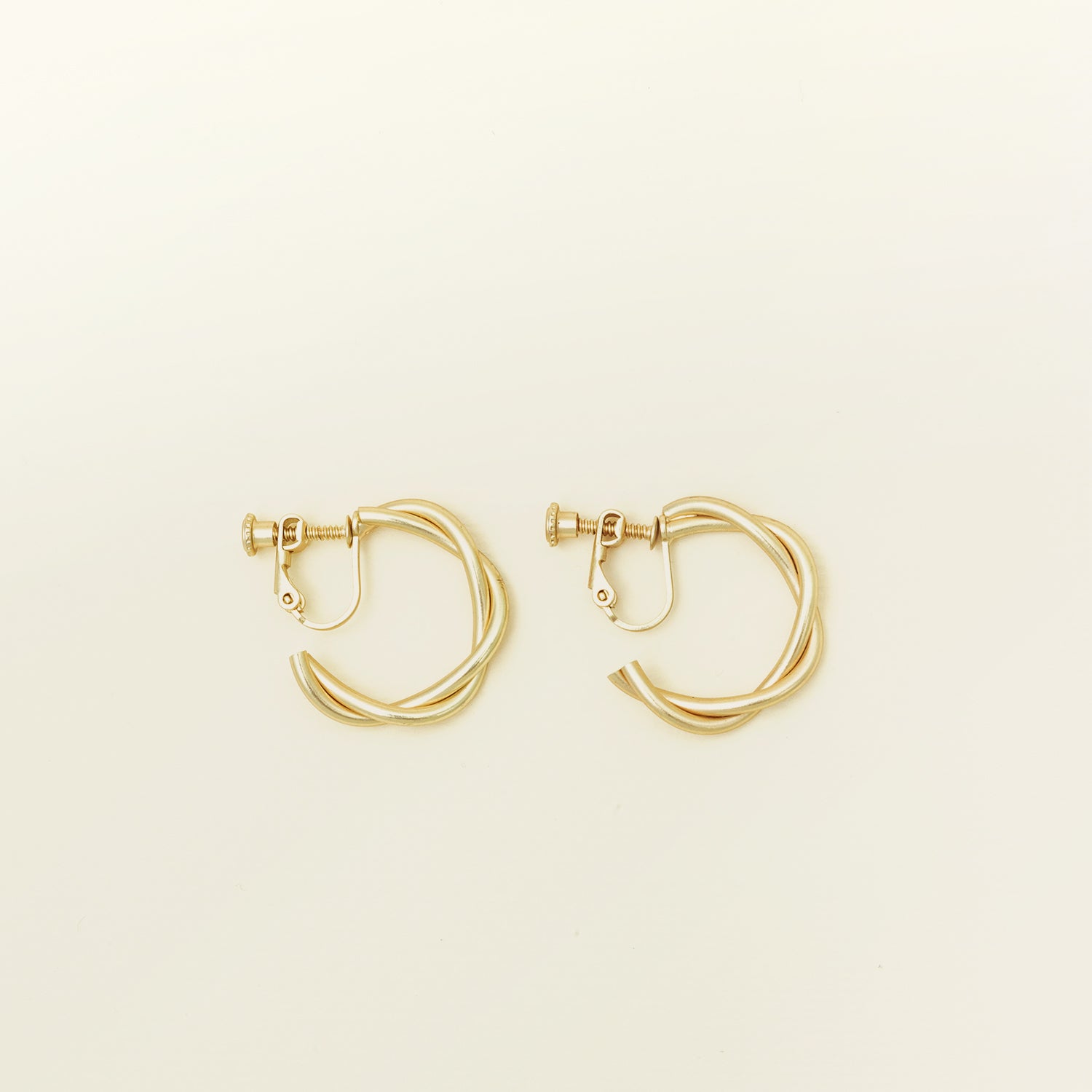 Image of the Twist Hoop Earrings feature a secure and comfortable screwback clip-on closure ideal for all ear types. Wear these earrings for up to 8-12 hours per day with a secure hold and the ability to be manually adjusted to the individual's size. Crafted from gold tone plated copper alloy, these earrings come is a single pair.