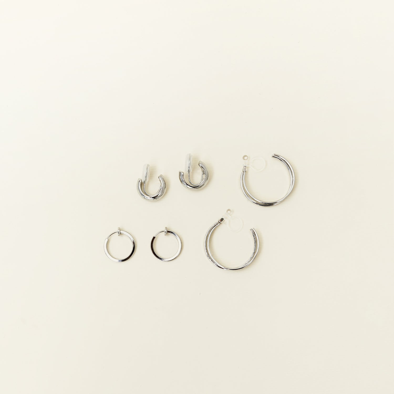 Image of the Everyday Essentials Set features three closure types: invisible resin, sliding spring and mosquito coil. It includes a Simple Silver Huggie Clip-On, Mini Hoop Earrings and Silver Cassie Hoop Earrings. Crafted from copper alloy, stainless steel and silver tone metal alloy, this item comes with three pairs and is also available in Gold.