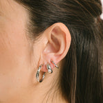 A model wearing the Everyday Essentials Set features three closure types: invisible resin, sliding spring and mosquito coil. It includes a Simple Silver Huggie Clip-On, Mini Hoop Earrings and Silver Cassie Hoop Earrings. Crafted from copper alloy, stainless steel and silver tone metal alloy, this item comes with three pairs and is also available in Gold.