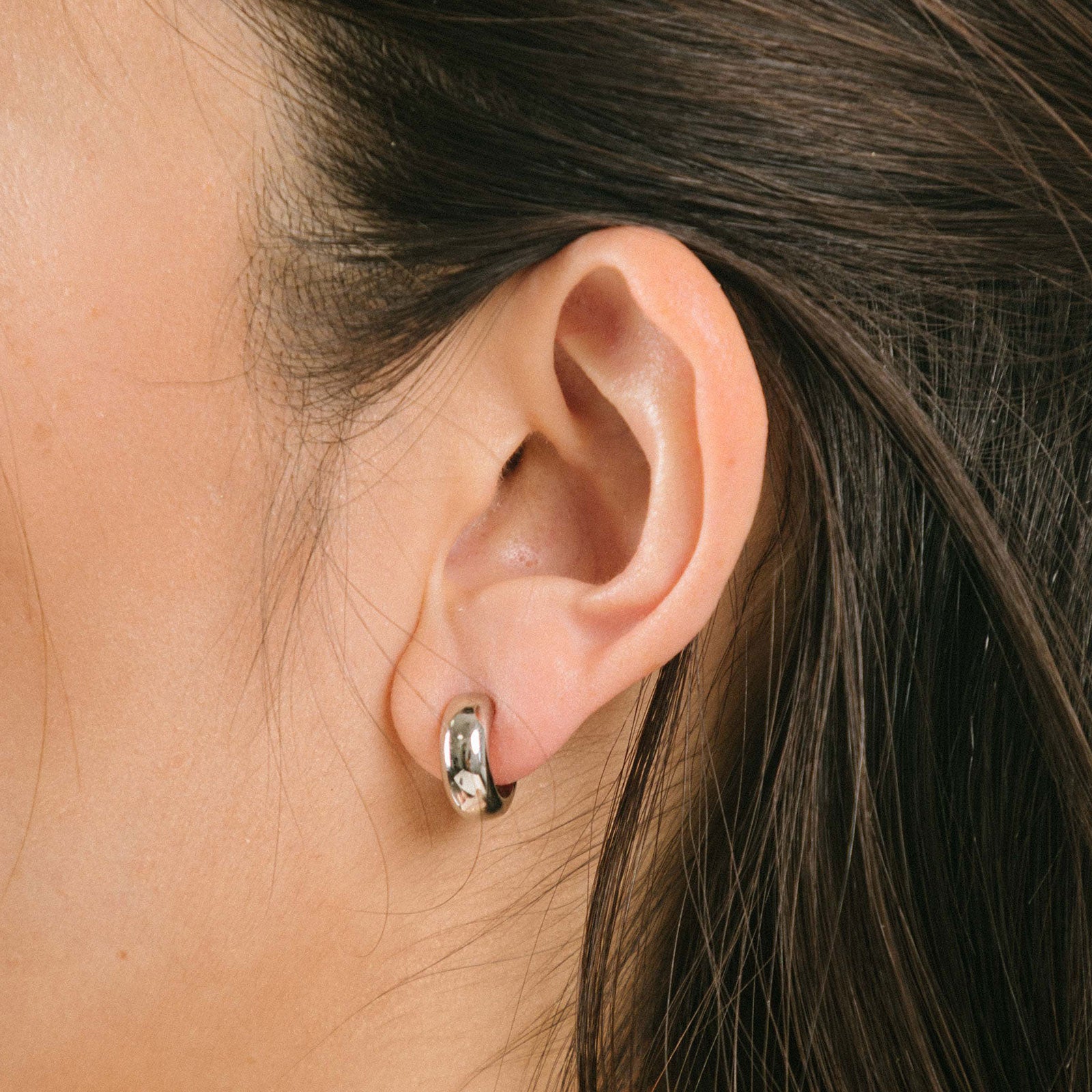A model wearing the Everyday Essentials Set features three closure types: invisible resin, sliding spring and mosquito coil. It includes a Simple Silver Huggie Clip-On, Mini Hoop Earrings and Silver Cassie Hoop Earrings. Crafted from copper alloy, stainless steel and silver tone metal alloy, this item comes with three pairs and is also available in Gold.