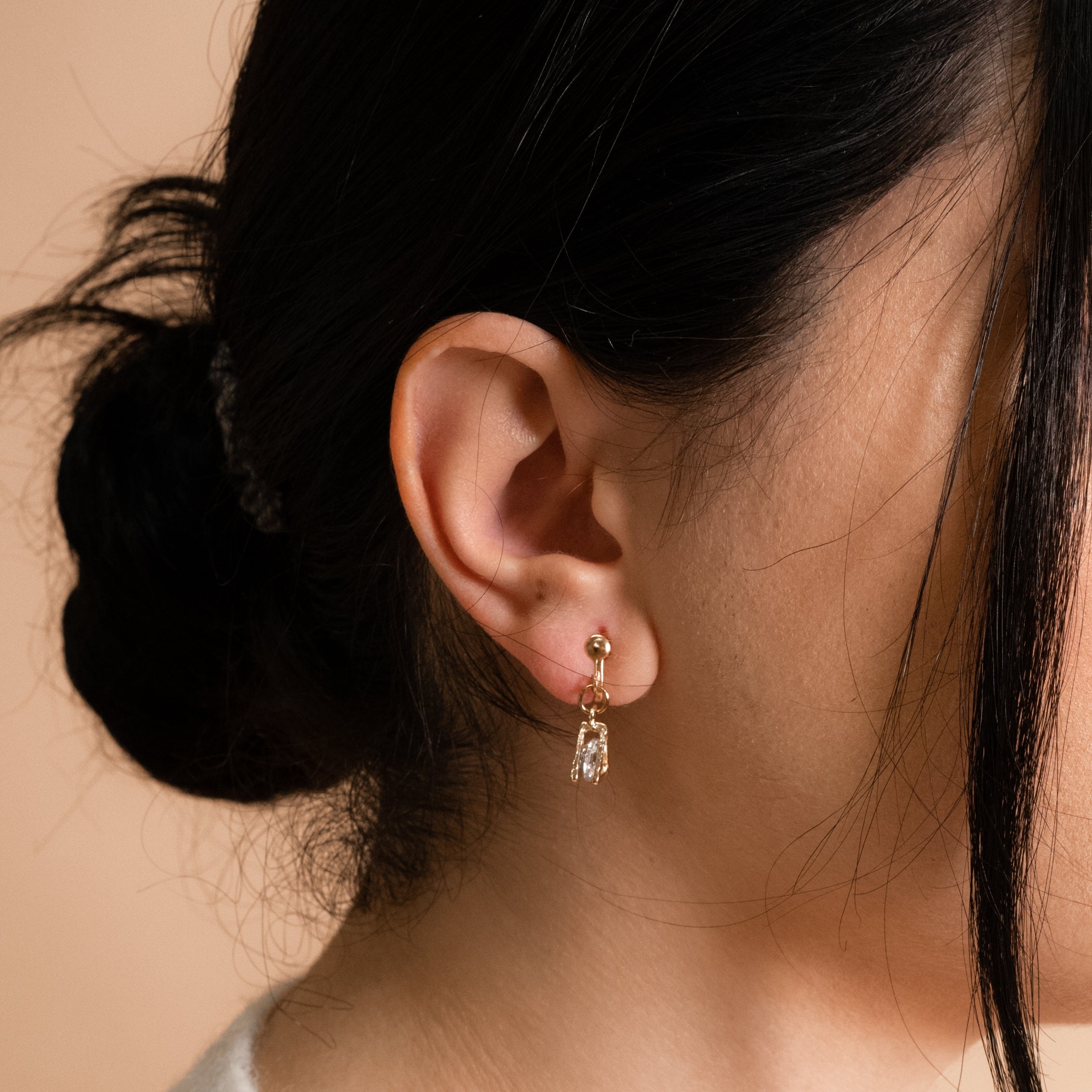 A model wearing Cecile Clip-On Earrings. Make a stylish addition to any ensemble with their gold-tone plated zinc alloy and sparkle of cubic zirconia. The removable rubber padding ensures comfort for thick, large, sensitive, small, and thin ears.