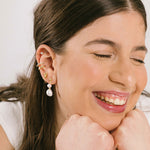 A model wearing the Duo Pearl Clip-On Earrings in Gold feature a mosquito coil clip-on closure ideal for all ear types. Enjoy medium secure hold and comfortable wear for up to 24 hours - gently squeezing the padding forward once on the ear for adjustable fit. Crafted with freshwater pearls and 18K gold plated stainless steel, each piece features unique natural variations in size and colour.