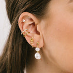 A model wearing the Duo Pearl Clip-On Earrings in Gold feature a mosquito coil clip-on closure ideal for all ear types. Enjoy medium secure hold and comfortable wear for up to 24 hours - gently squeezing the padding forward once on the ear for adjustable fit. Crafted with freshwater pearls and 18K gold plated stainless steel, each piece features unique natural variations in size and colour.