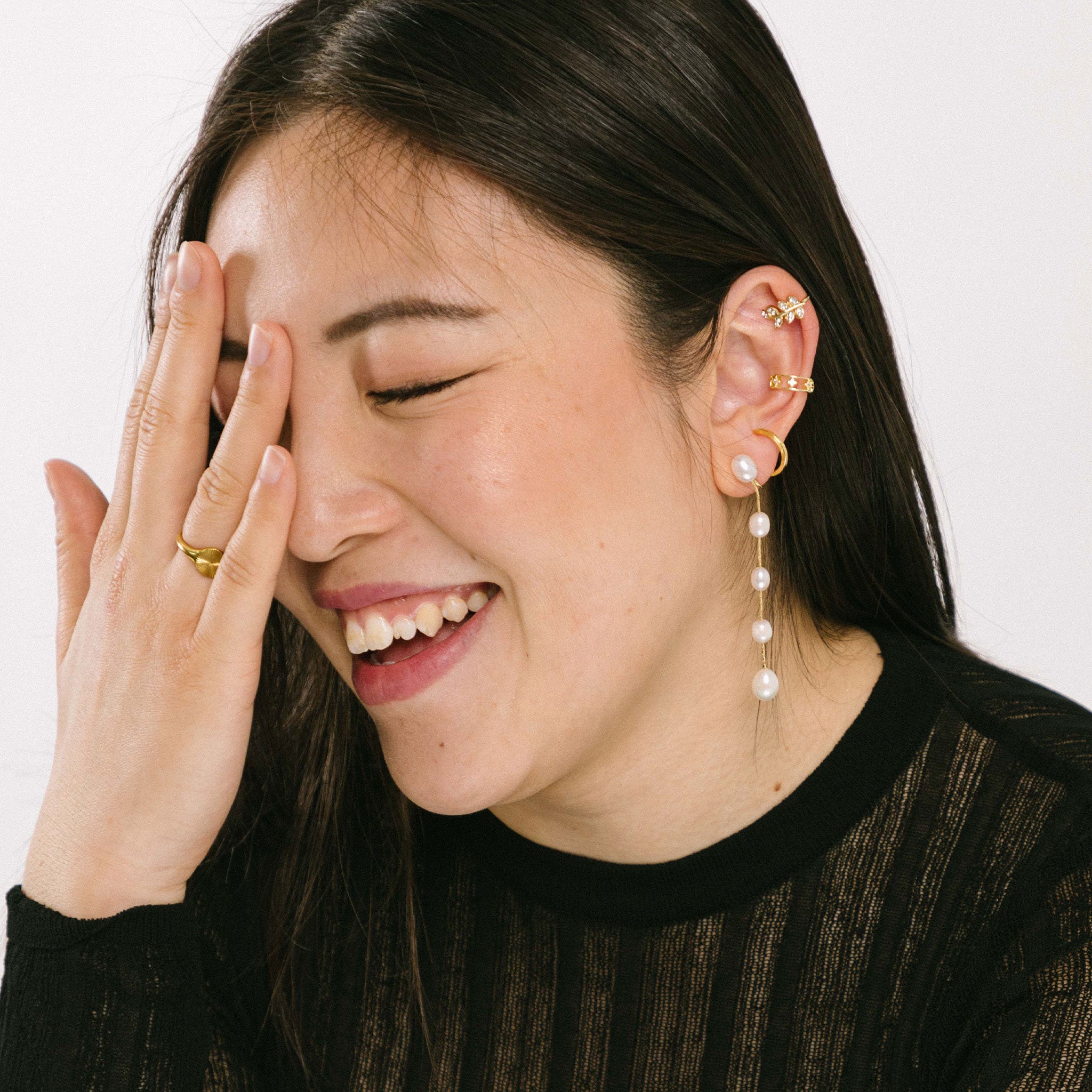 A model wearing the Lune Pearl Clip-On Earrings in Gold feature a unique, secure mosquito coil clasp. They are ideal for all ear types, from thick and large ears to sensitive and small. With medium hold strength, the earrings can be comfortably worn up to 24 hours and easily adjusted. Crafted with freshwater pearls, each pair may display natural variations in size and color. Materials include freshwater pearl and 18K gold-plated stainless steel.