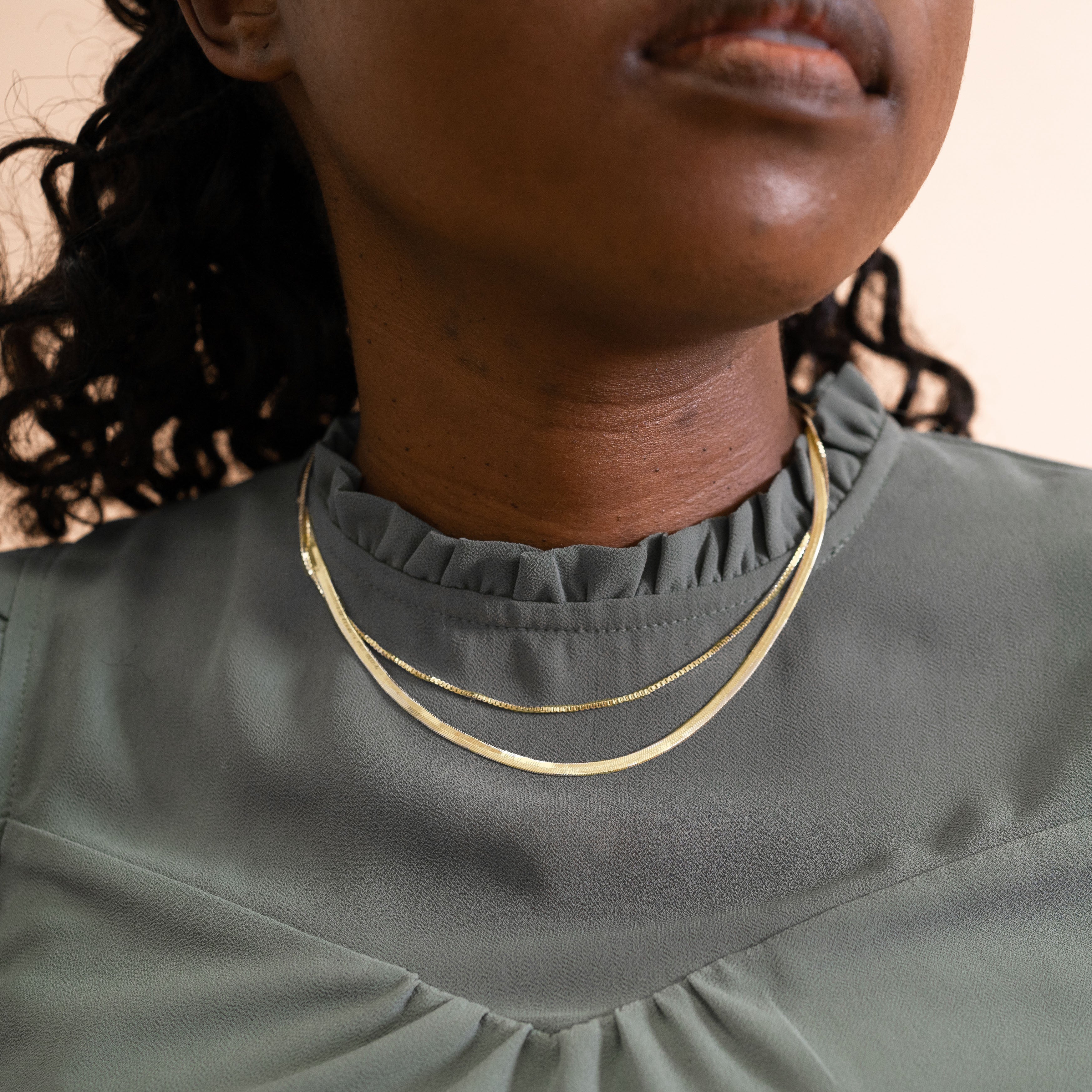 A model wearing the Double Layered Chain Necklace In Gold. This necklace features an adjustable design, and is crafted from 18K Gold Plated Vermeil on Sterling Silver with waterproof and non-tarnish properties. It is also available in Silver.