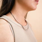 A model wearing the Double Layered Chain Necklace In Silver is adjustable, constructed of stainless steel and is waterproof and non-tarnish. It is also available in Gold.