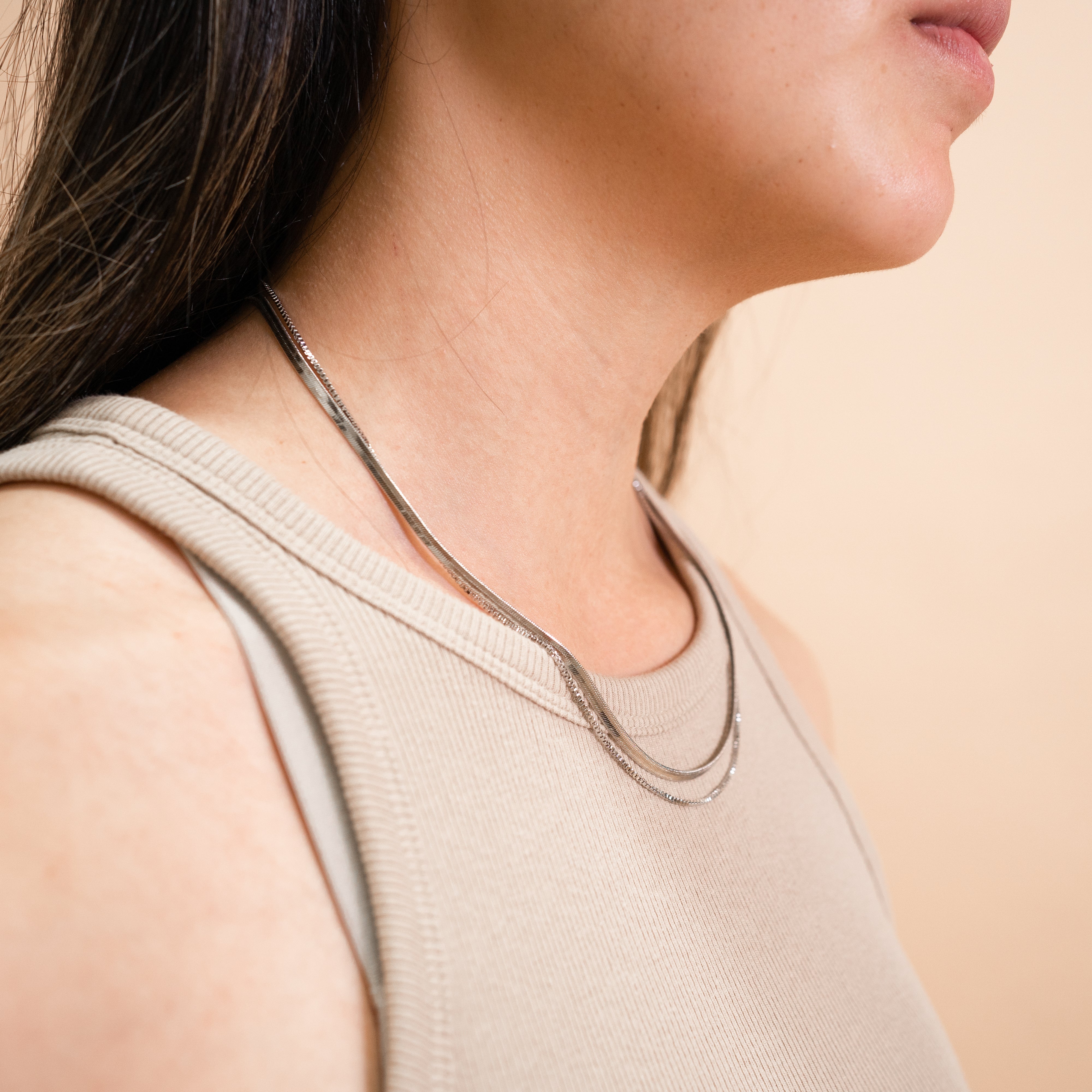 A model wearing the Double Layered Chain Necklace In Silver is adjustable, constructed of stainless steel and is waterproof and non-tarnish. It is also available in Gold.