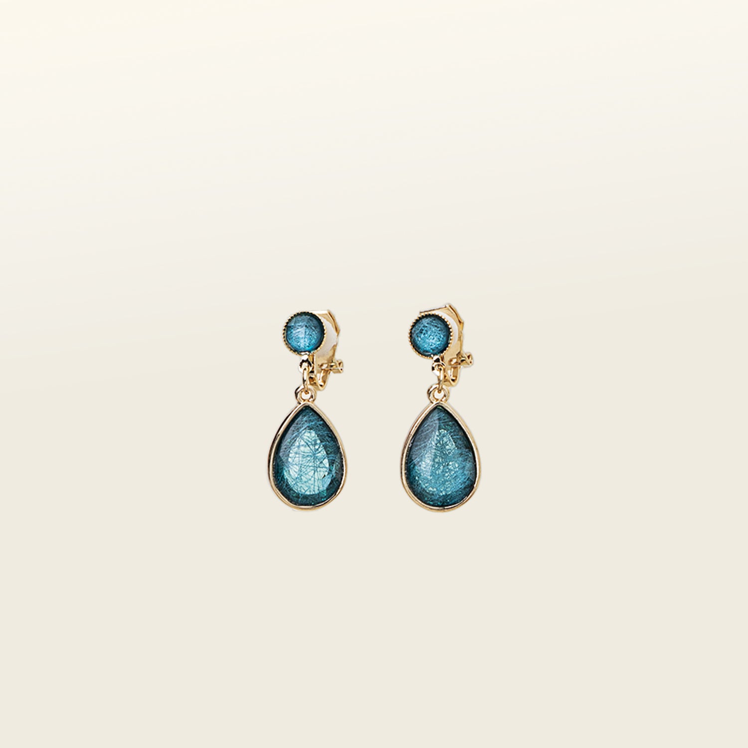 Image of the Sabrina Blue Tear Drop Clip-On Earrings feature a padded clip closure, making them ideal for all ear types. The earrings offer secure hold for up to 8-12 hours and are constructed of resin and gold tone plated zinc alloy. For extra comfort, the earrings come with removable rubber padding and cannot be adjusted for size. Please note, one package contains one pair of earrings.